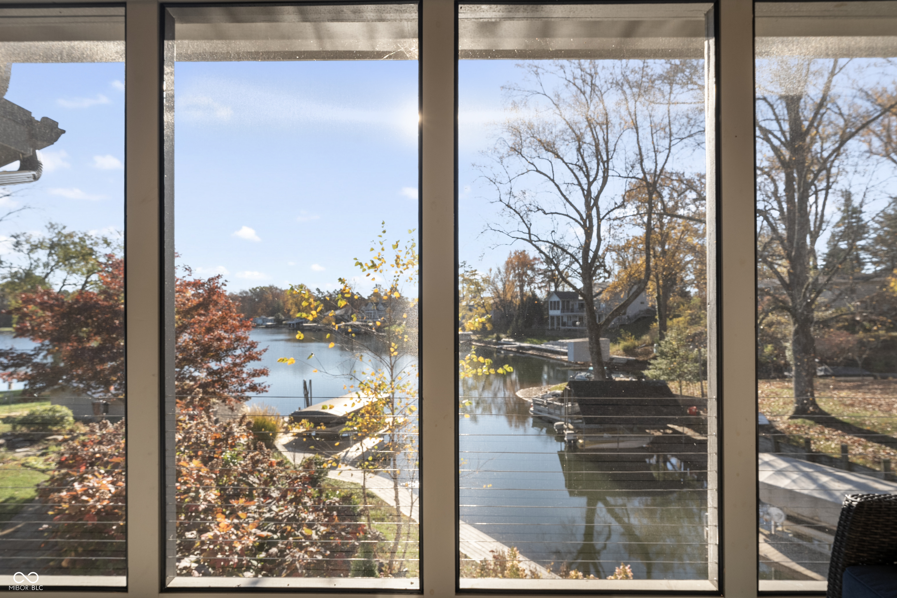 Lake and docks seen through large windows, with autumn trees along the shoreline.