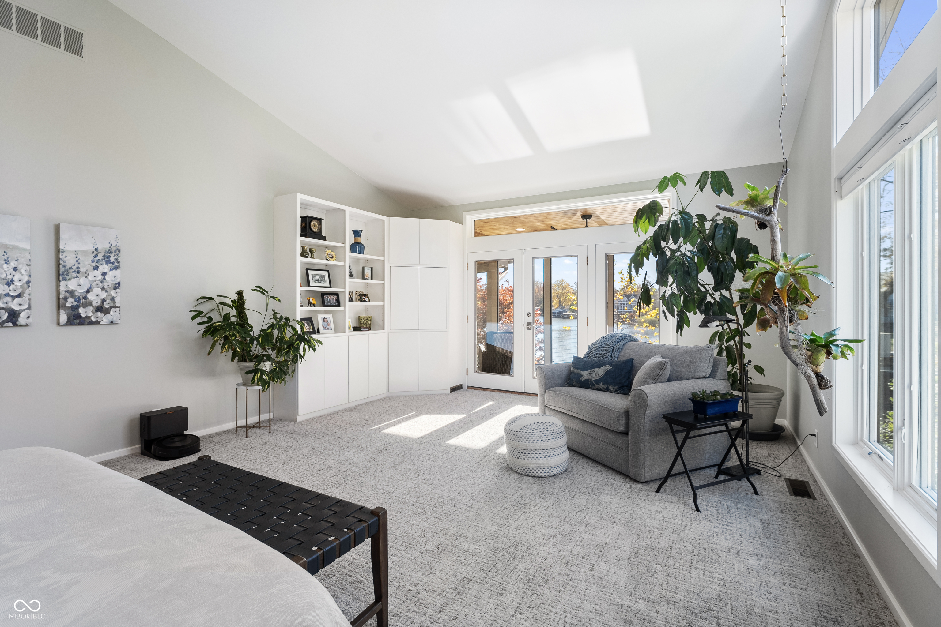 Bedroom sitting area with gray sofa, built-in shelving, and glass doors overlooking the water.