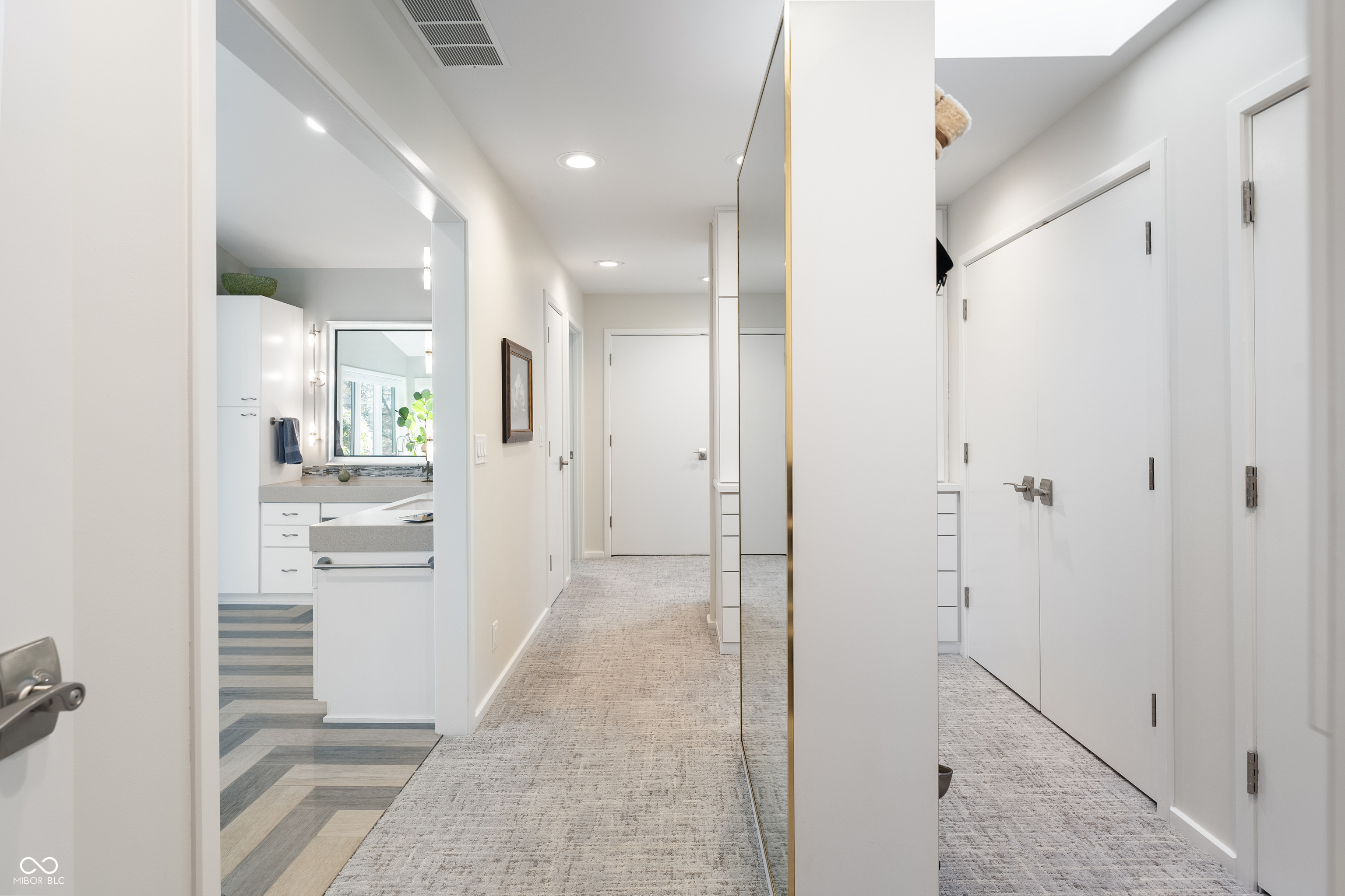 Bright hallway with mirrored closet doors and a view into a bathroom vanity area.