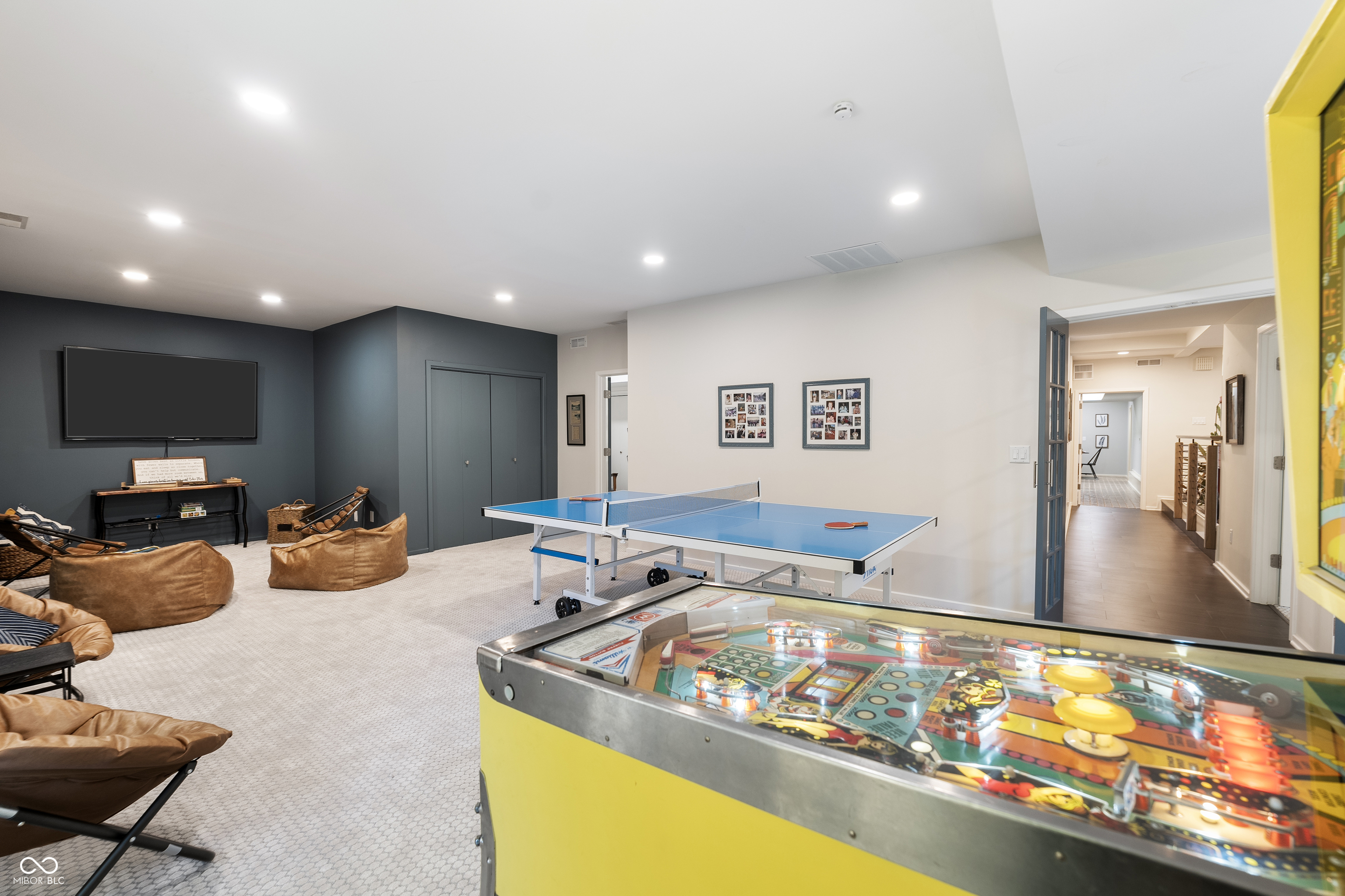 Game room with a ping-pong table, yellow pinball machine, and brown lounge seating.
