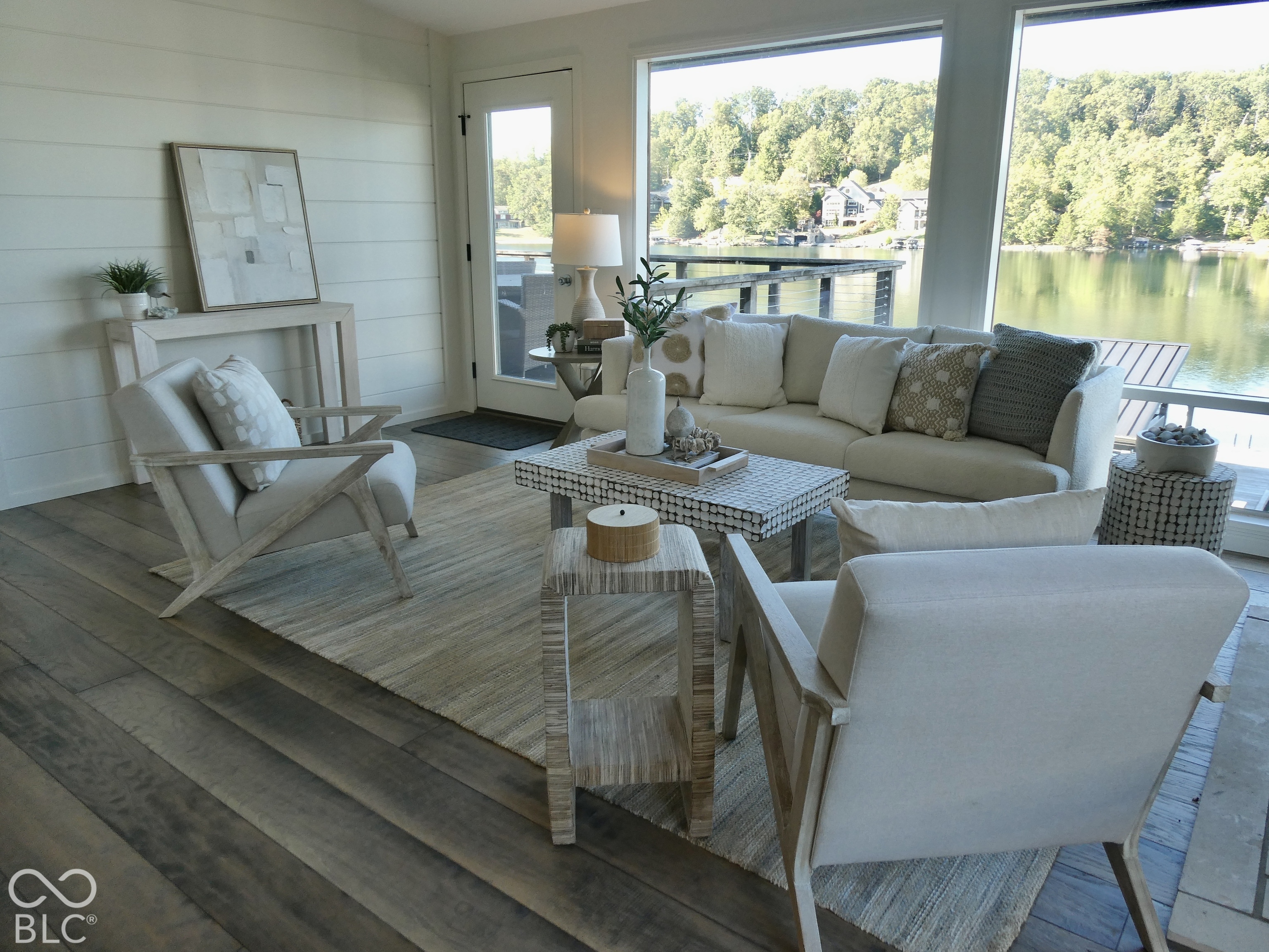 Staged living room with lake views through wide windows and a deck outside.