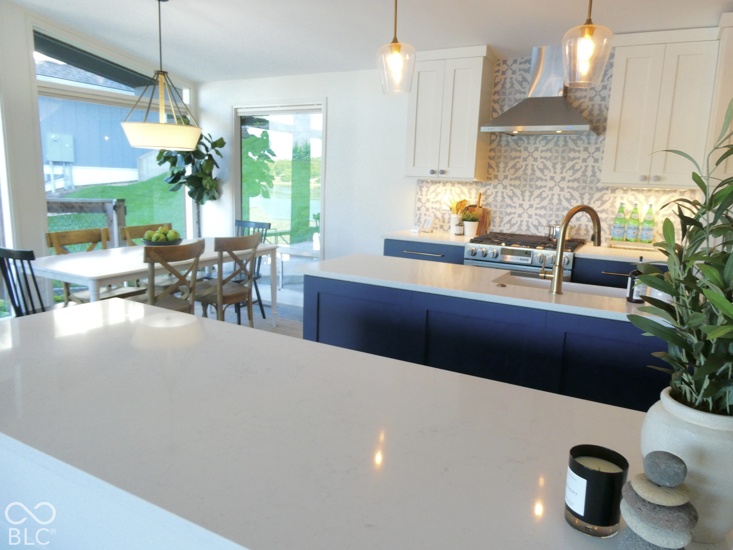 Kitchen with blue cabinets, patterned backsplash, large island, and dining nook by glass doors.