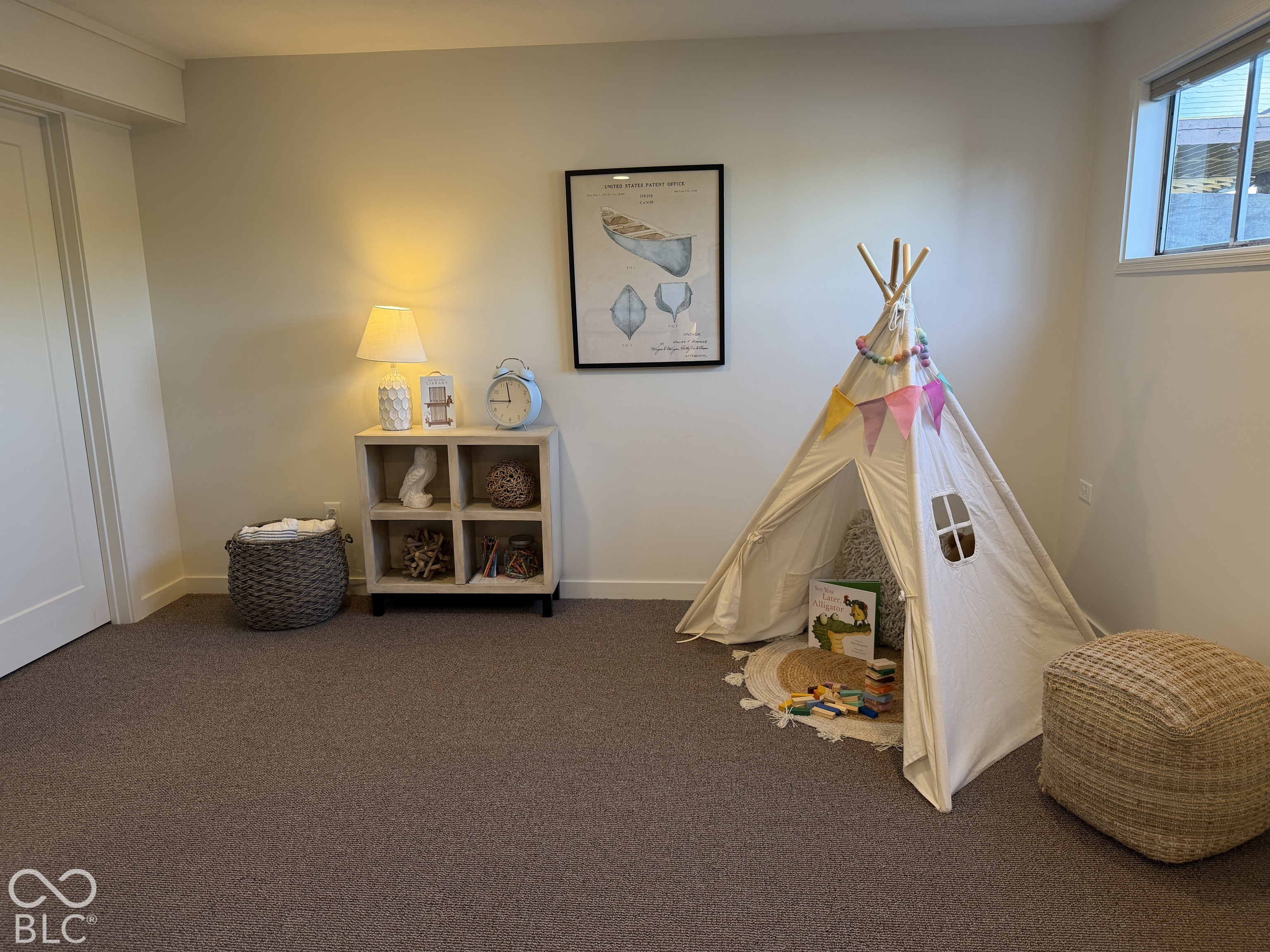 Children’s playroom with a canvas teepee, colorful bunting, toy shelf, and woven baskets.