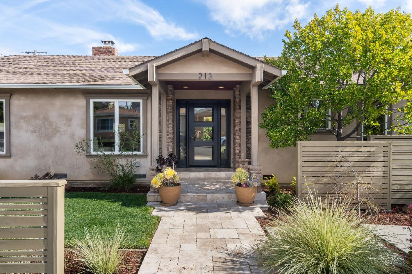 Home entrance with a covered porch, dark front door, and landscaped walkway.