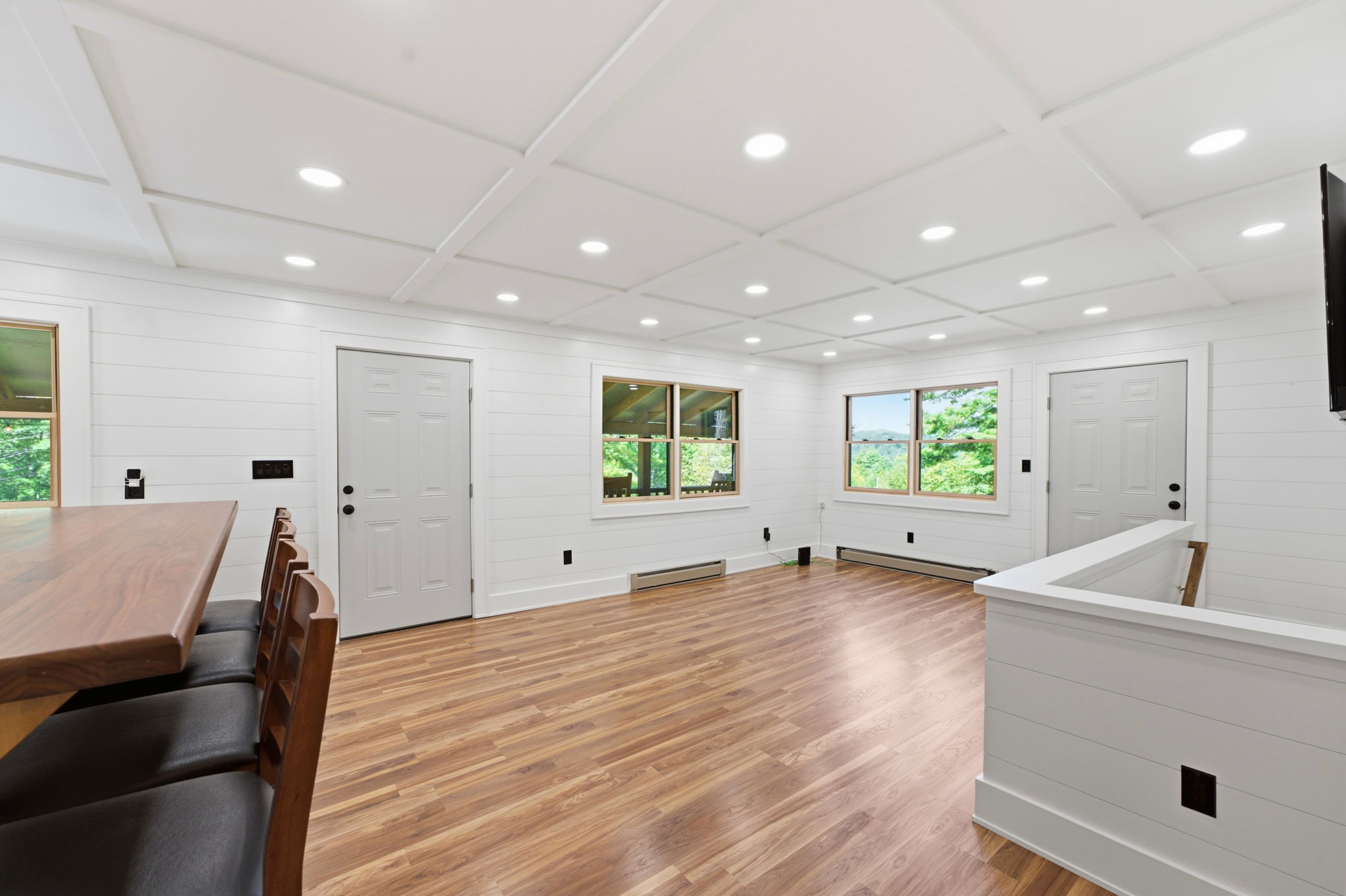 Bright open room with a coffered ceiling, wood-look floors, and a counter with stools.