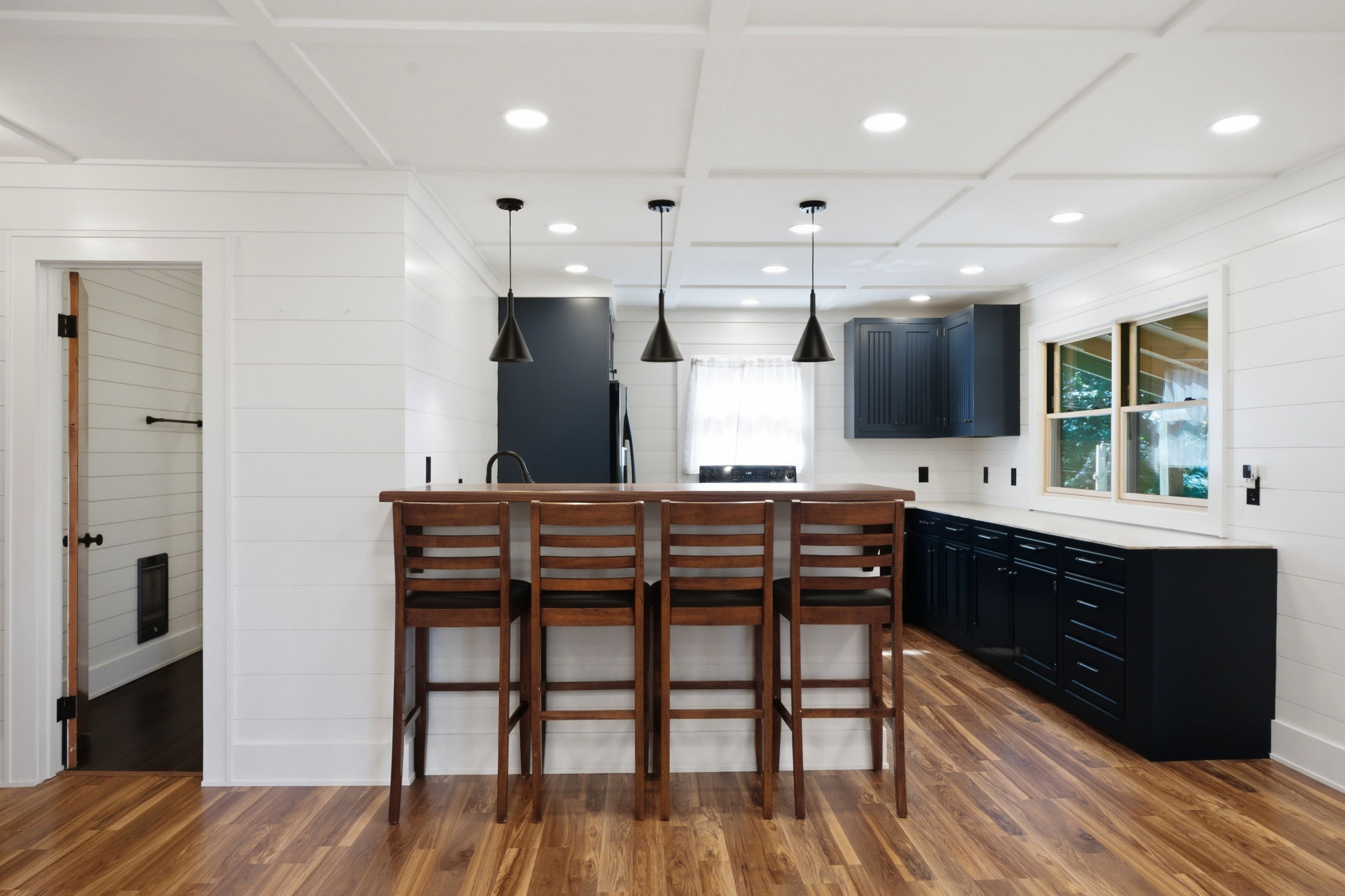 Kitchen with navy cabinets, a wood-topped island, four bar stools, and hardwood floors.
