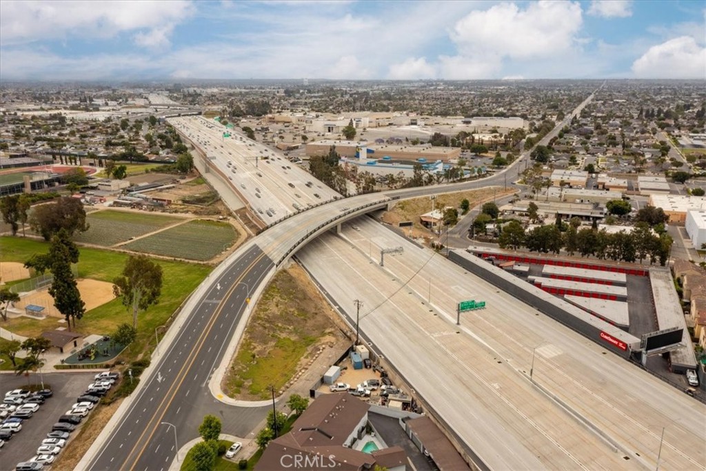 Aerial view of a freeway interchange surrounded by urban development and a sports field.