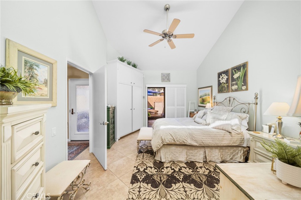 Furnished bedroom with white built-in wardrobes, a metal bed frame, ceiling fan, and patterned rug.