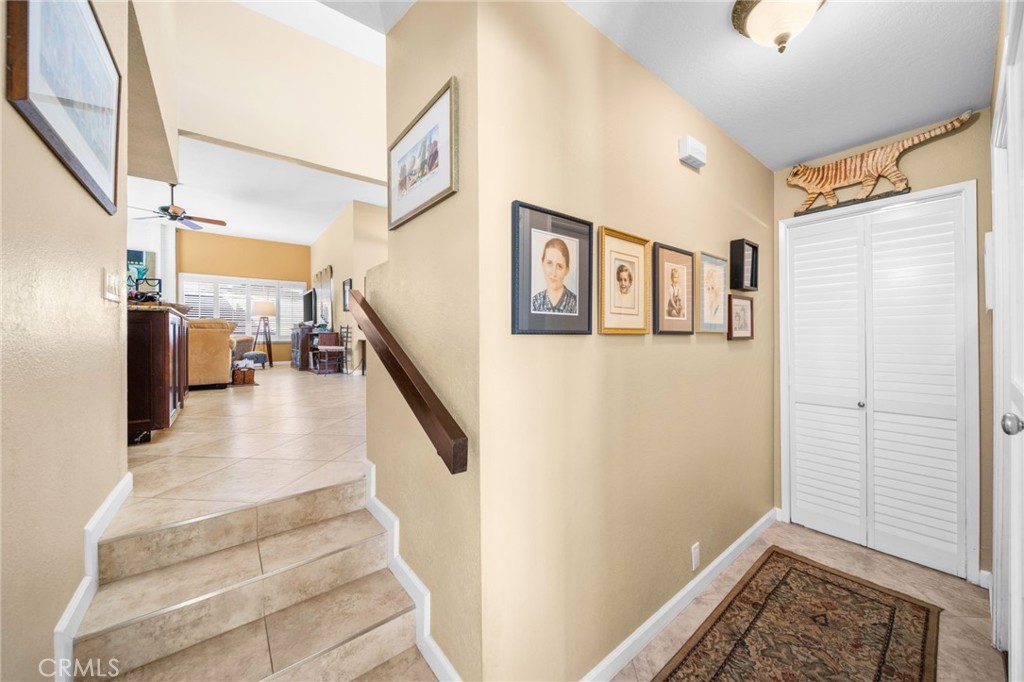 Entry hallway with tiled stairs, framed pictures, and white louvered closet doors.