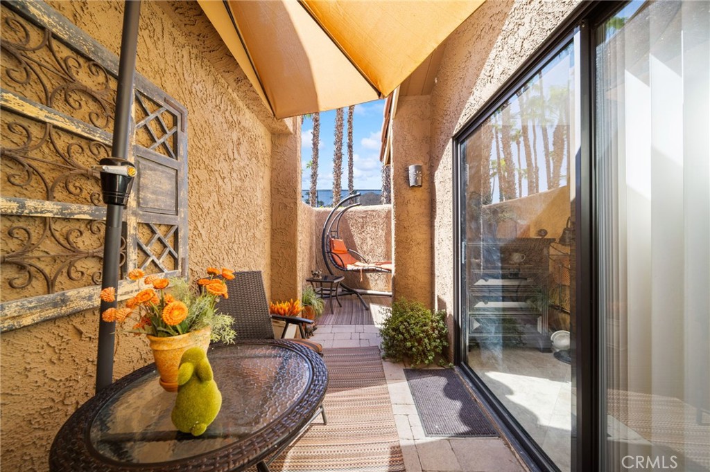 Furnished patio with a tan shade canopy, glass table, and sliding doors.