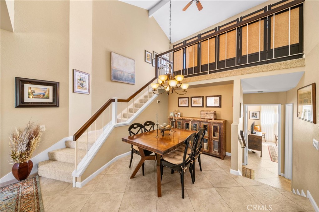 Dining room with a wooden table, carpeted staircase, and loft railing.