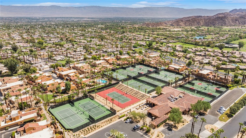 Aerial view of homes and tennis courts with mountains in the distance.