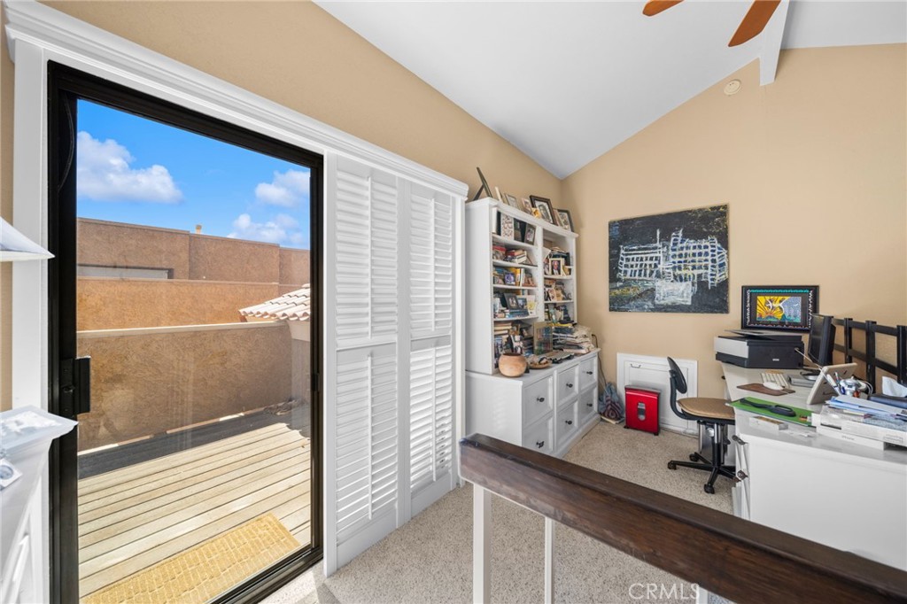 Home office with built-in shelving and a sliding glass door to a wooden balcony.