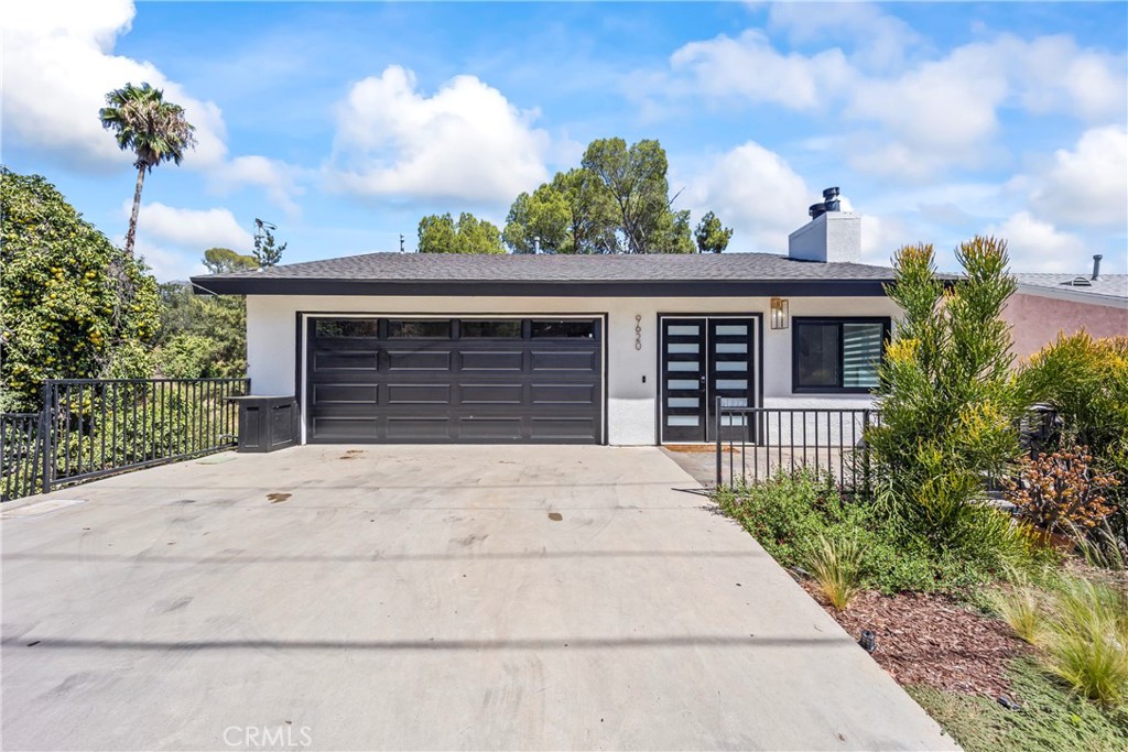 Single-story home with a dark double garage door, modern entry, and broad concrete driveway.