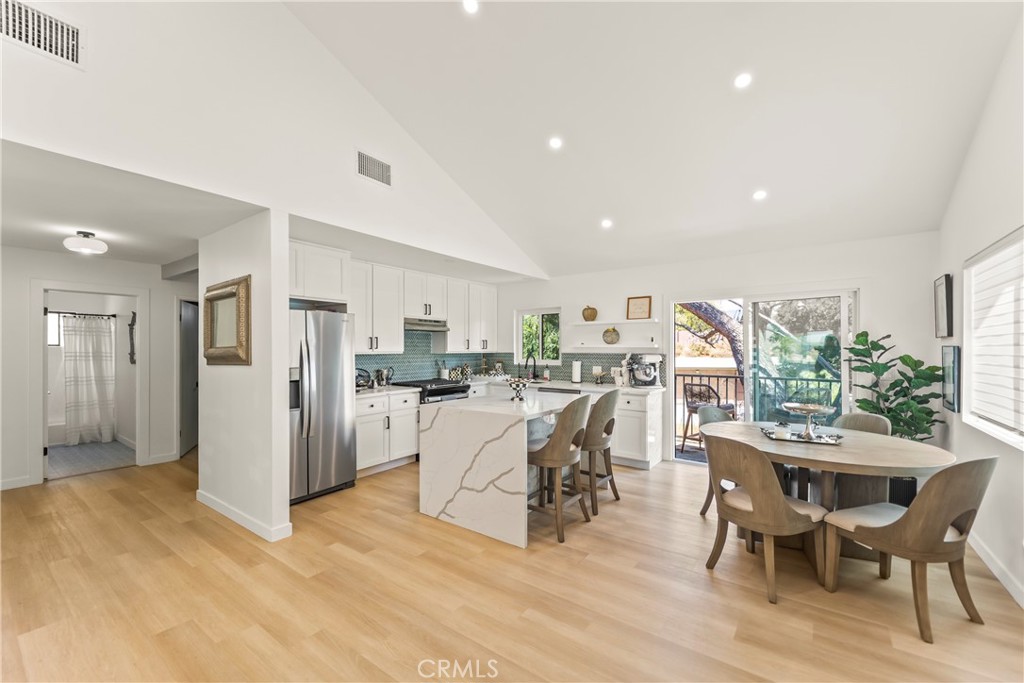 Open kitchen and dining area with a marble-look island, blue tile backsplash, and balcony access.
