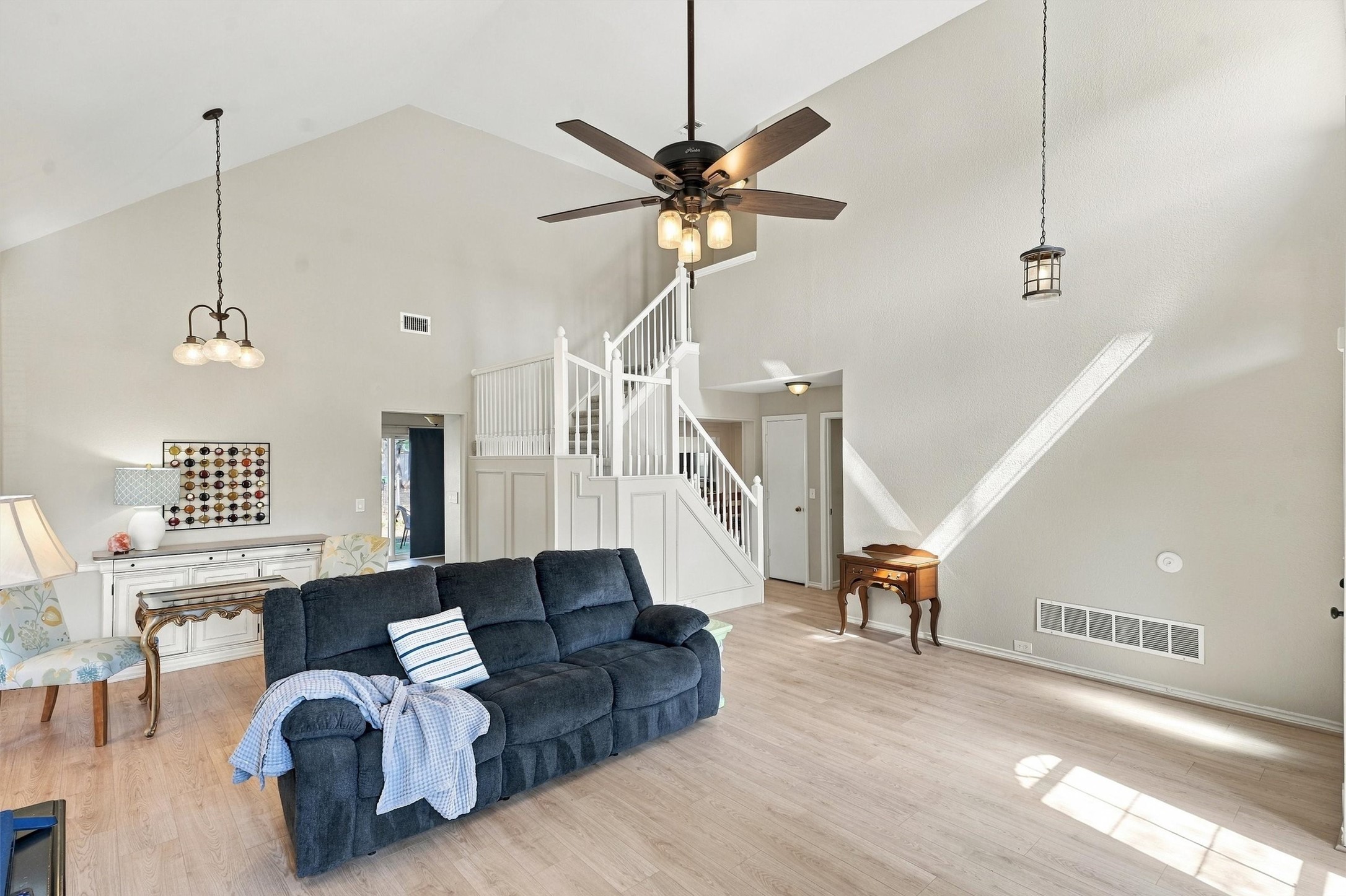 Living room with vaulted ceiling, white staircase, and dark blue reclining sofa.