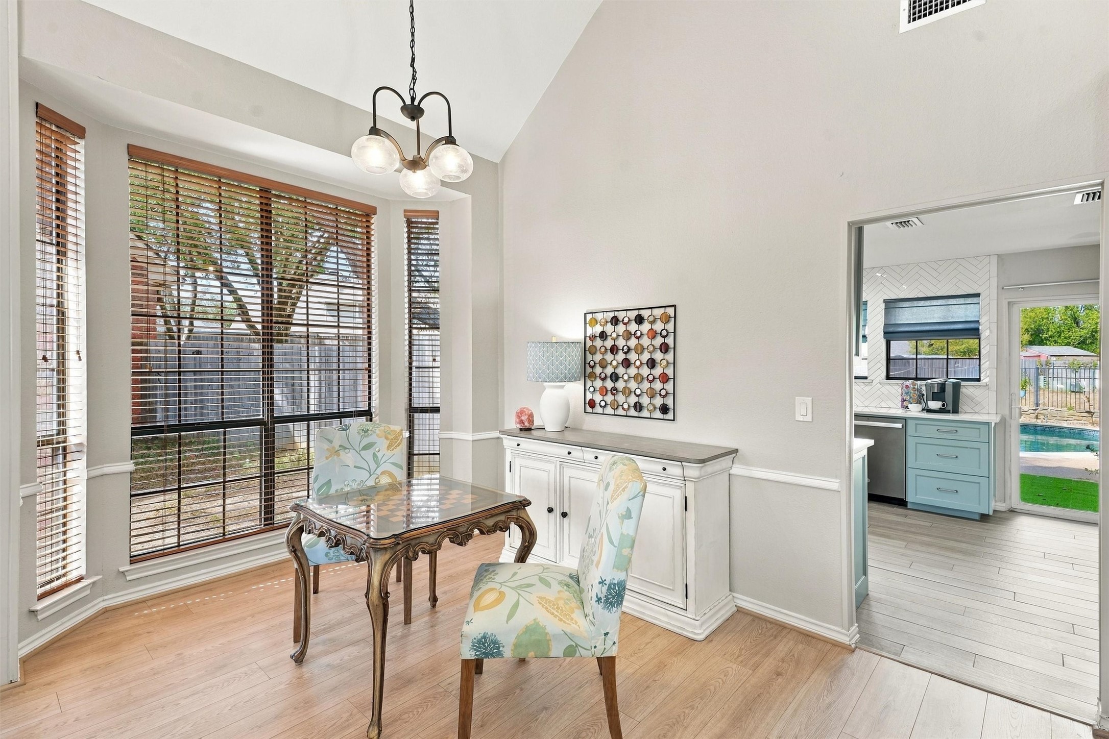 Dining room with bay windows, floral chairs, a built-in sideboard, and a view into the kitchen.
