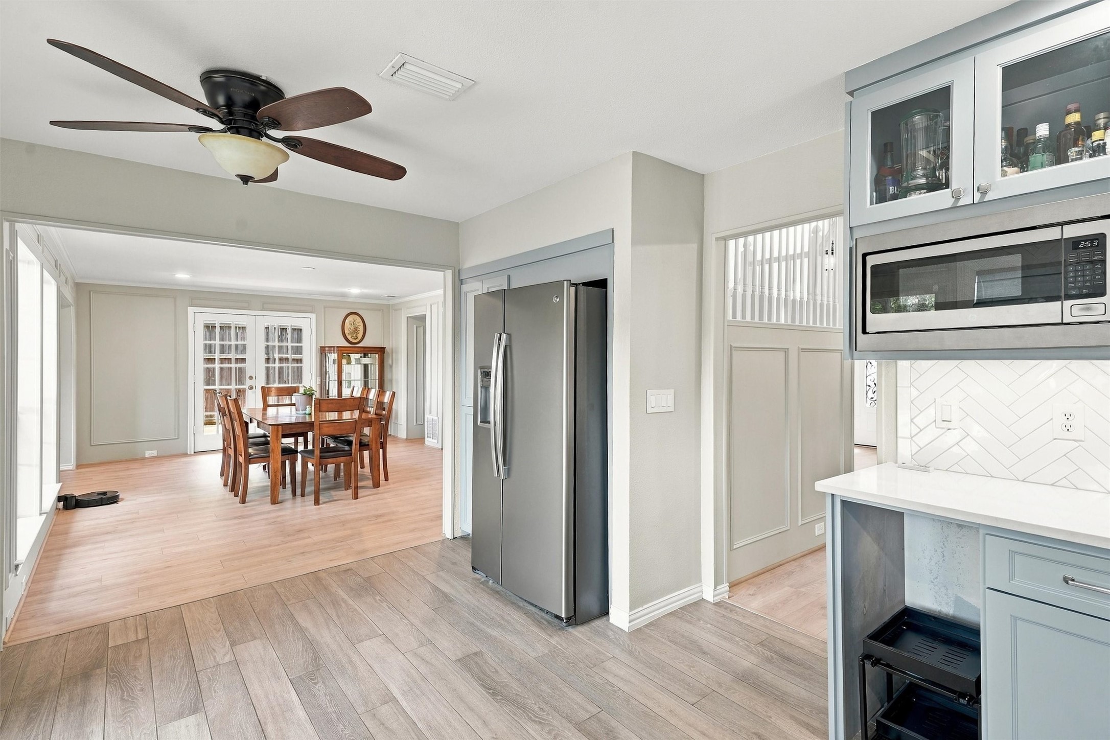 Kitchen with blue-gray cabinets and stainless appliances opening to a dining area with French doors.