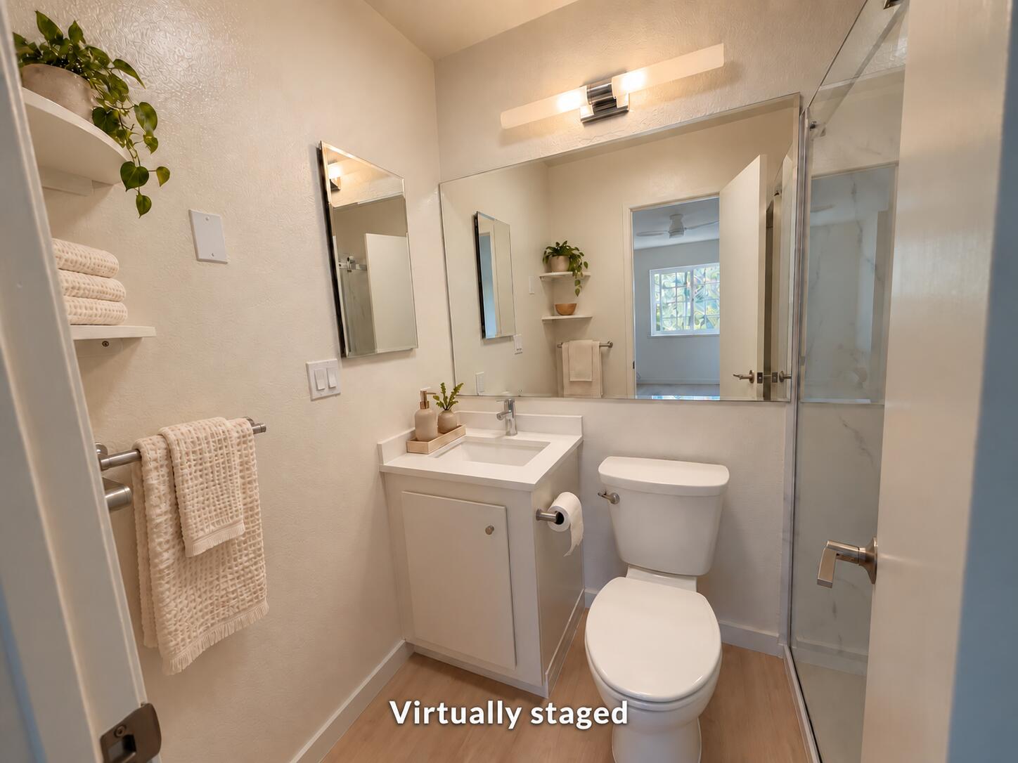 Virtually staged bathroom with a white vanity, toilet, and glass-enclosed shower.