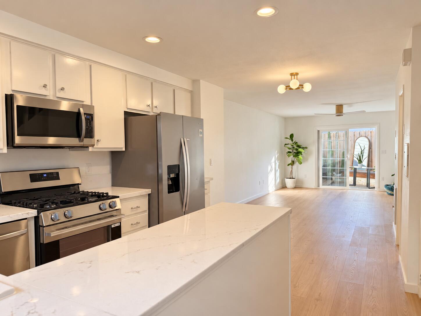 Open-plan kitchen with a large stone island, stainless appliances, and sliding doors to a patio.