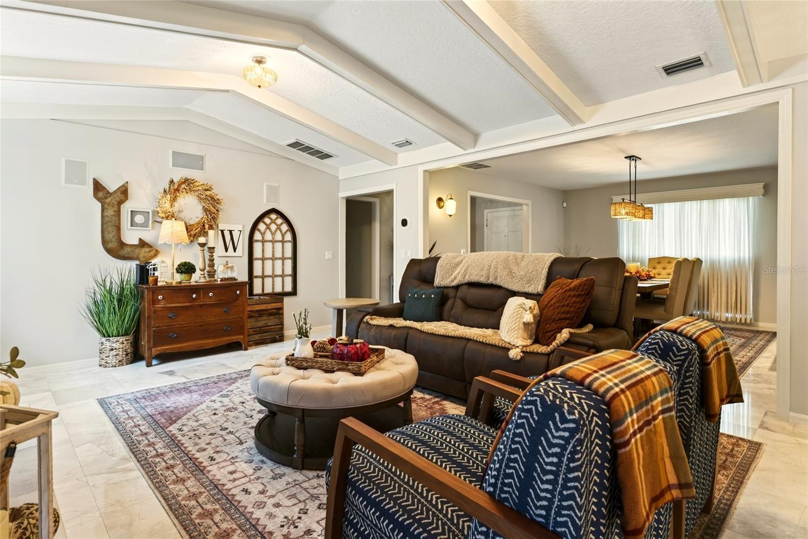 Furnished living room with a coffered ceiling, leather sofa, and open dining area.