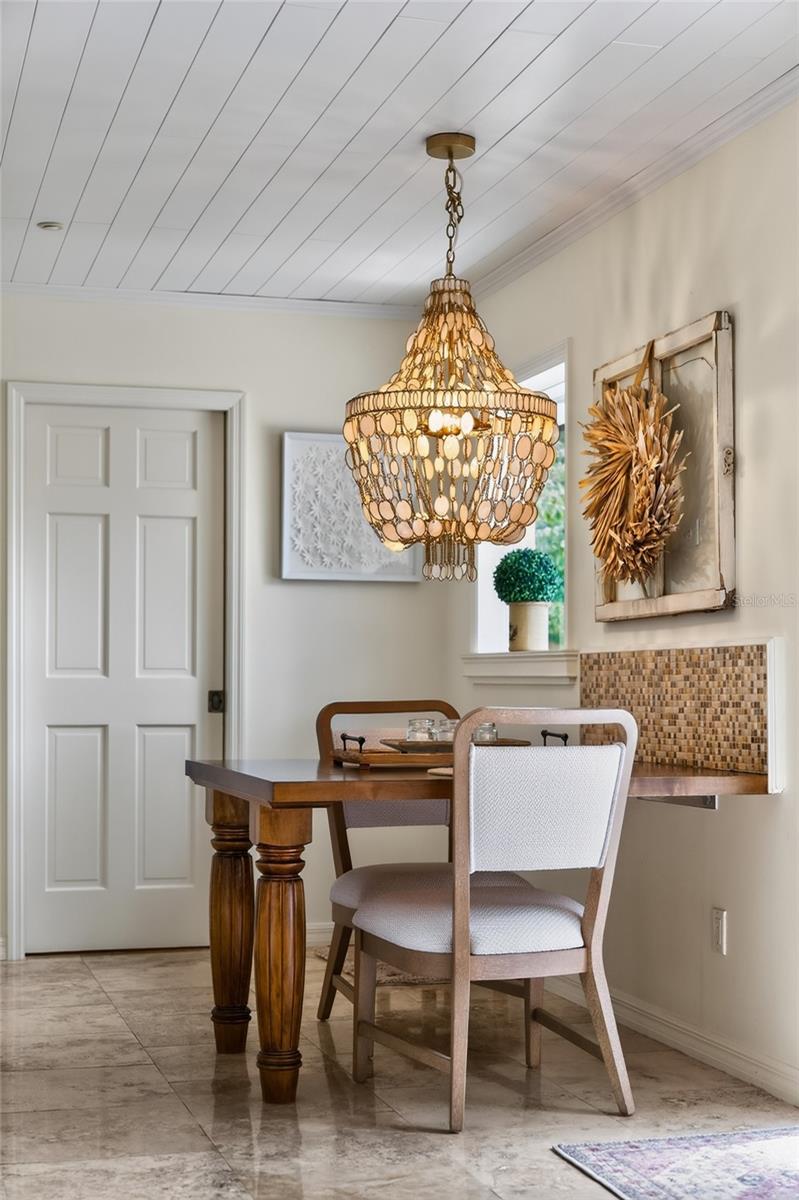Dining area with a dark wood table, upholstered chairs, and a large amber-toned chandelier.