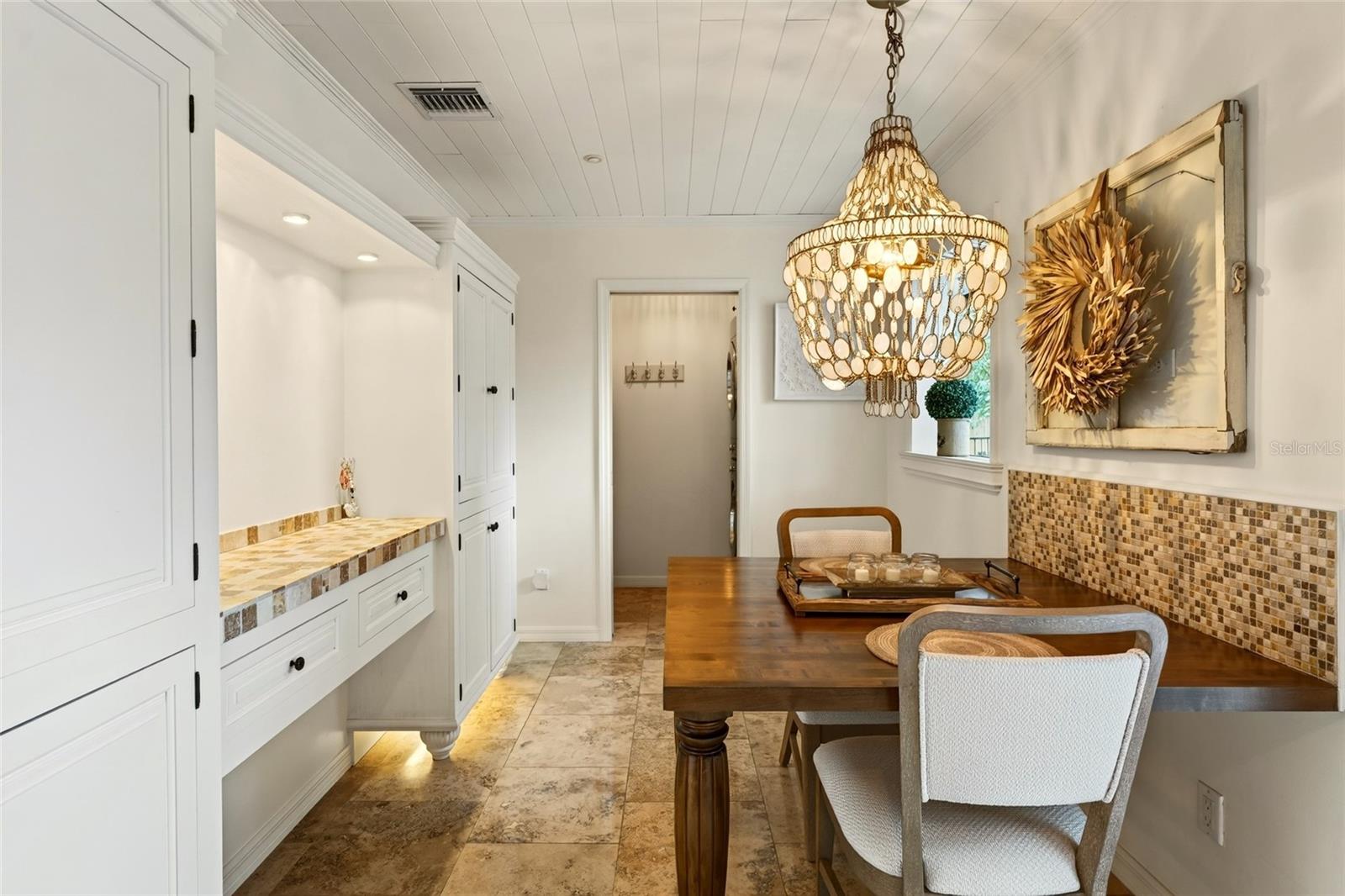 Dining area with a dark wood table, chandelier, and built-in white cabinetry.