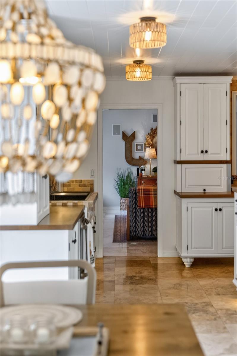 Kitchen with white paneled cabinets, stone counters, pendant lights, and a view into the dining area.