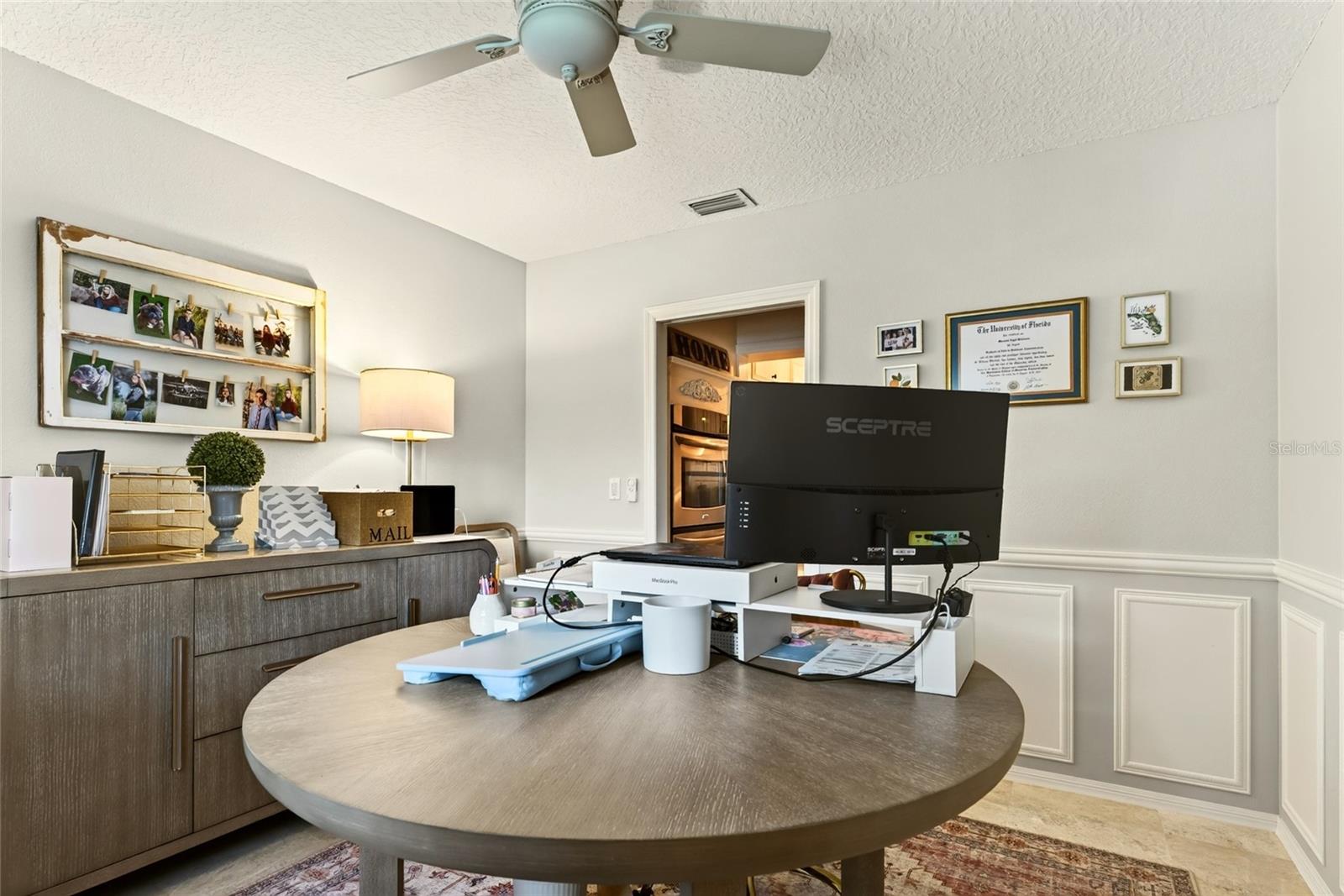 Home office with a round desk, computer monitor, and dark wood storage cabinet.