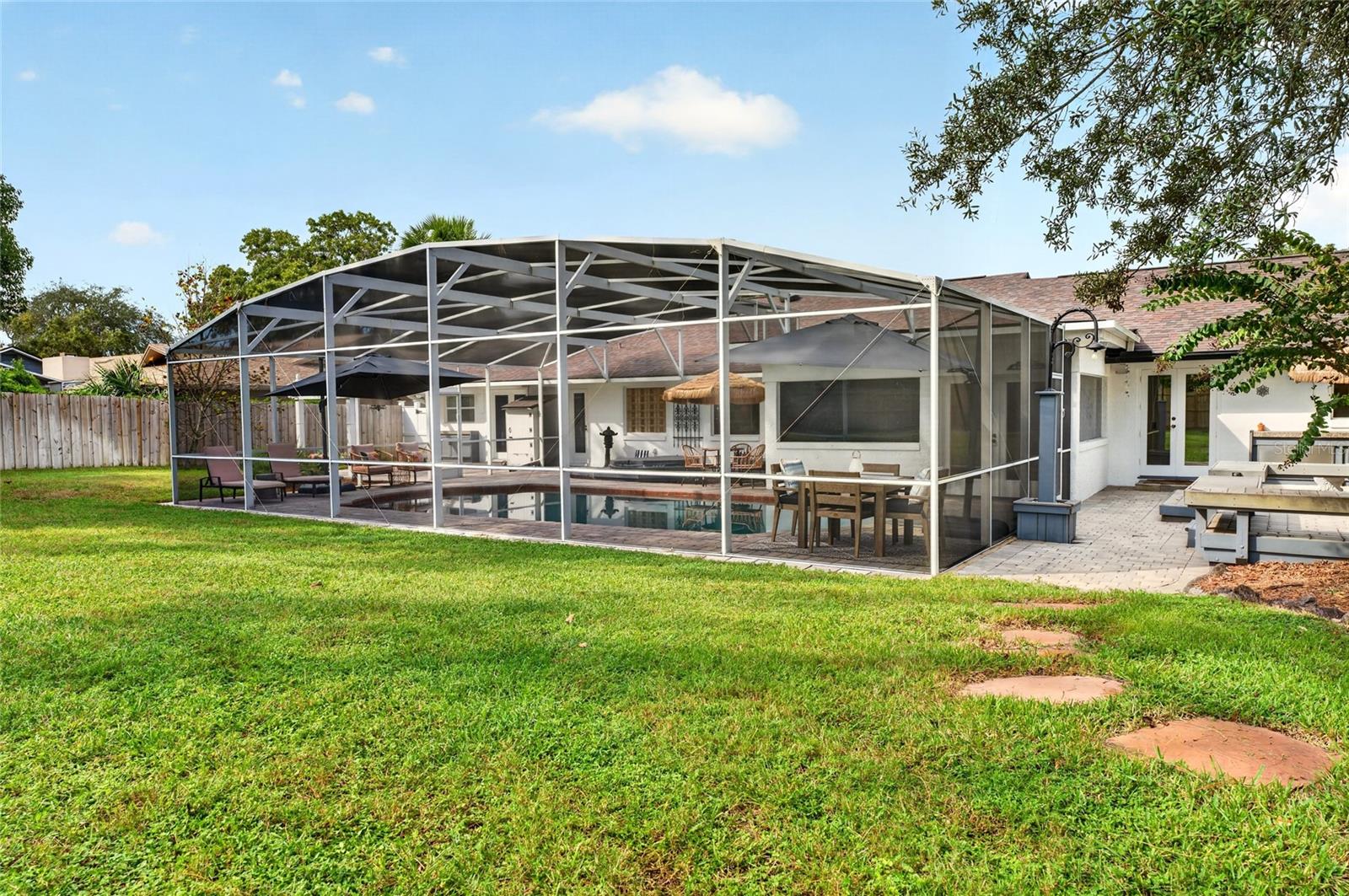 Screened backyard pool with patio dining area and lawn.