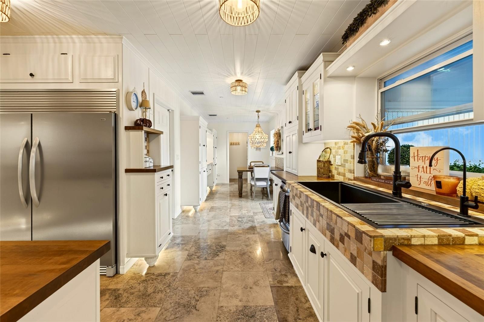 Kitchen with white cabinets, a black farmhouse sink, tiled counters, and wood countertops.