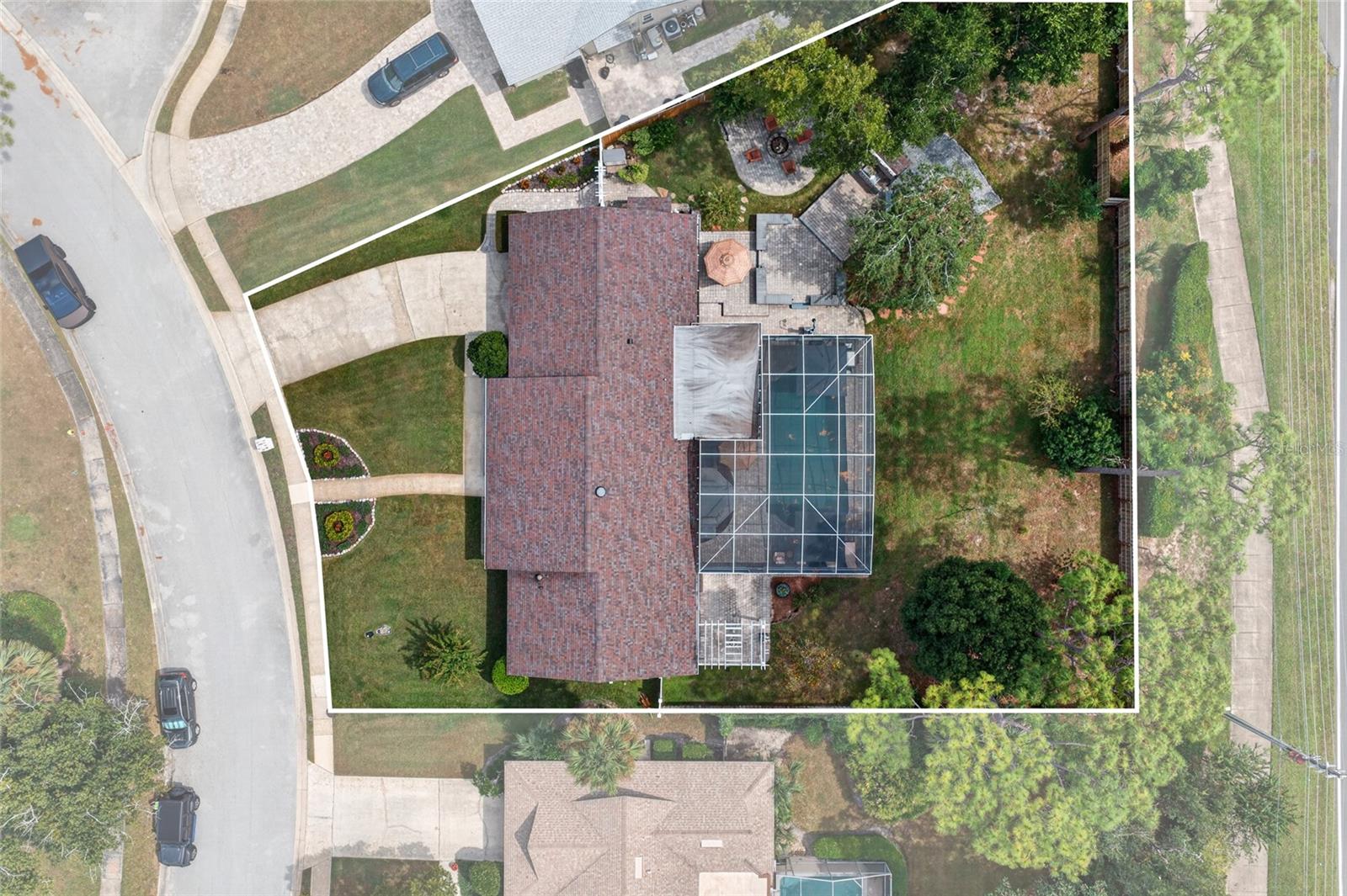 Aerial view of a home and property lot with a screened pool enclosure and landscaped yard.