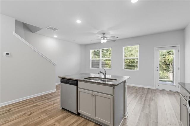 Vacant kitchen with a gray island, dark countertop, wood-look flooring, and glass patio door.