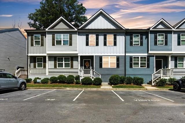 Attached two-story townhouse with gray and blue siding, white trim, and parking spaces in front.