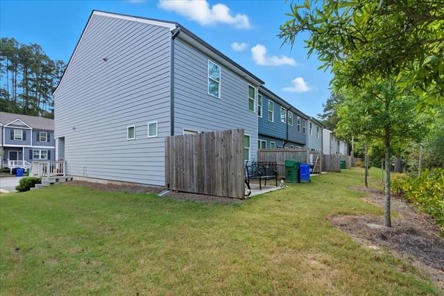 Rear and side exterior of a gray townhome with fenced patios and a grassy yard.