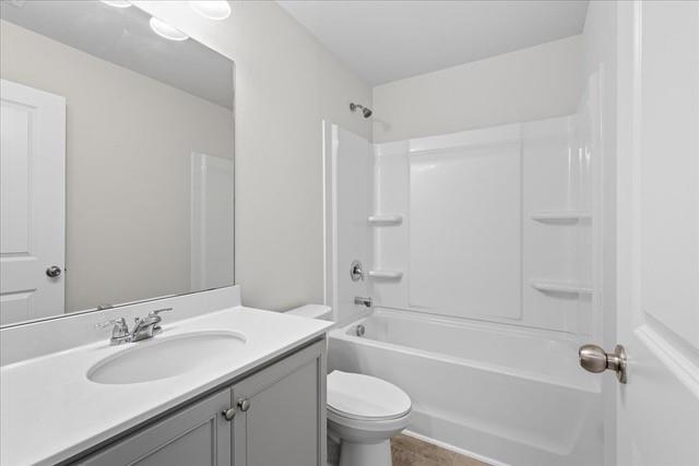 Bathroom with a white tub and shower, toilet, and gray vanity beneath a large mirror.