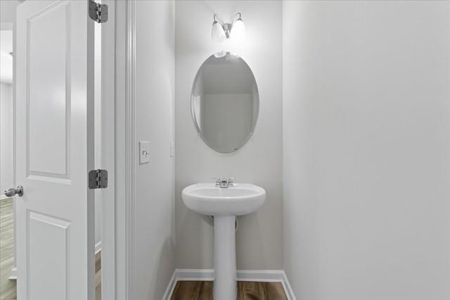 Small bathroom with a pedestal sink, oval mirror, and open paneled door.