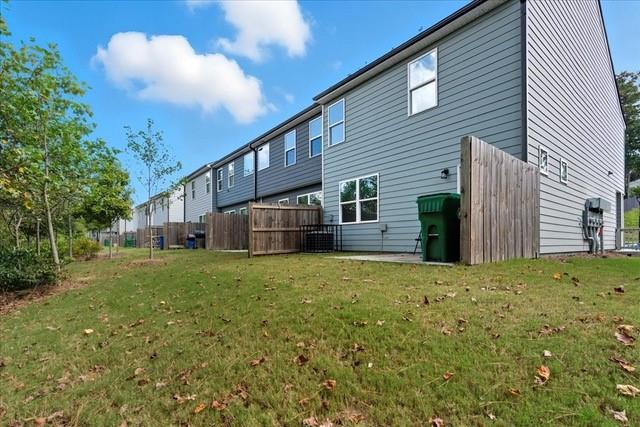 Gray-sided residential building with fenced patios along a grassy lawn.