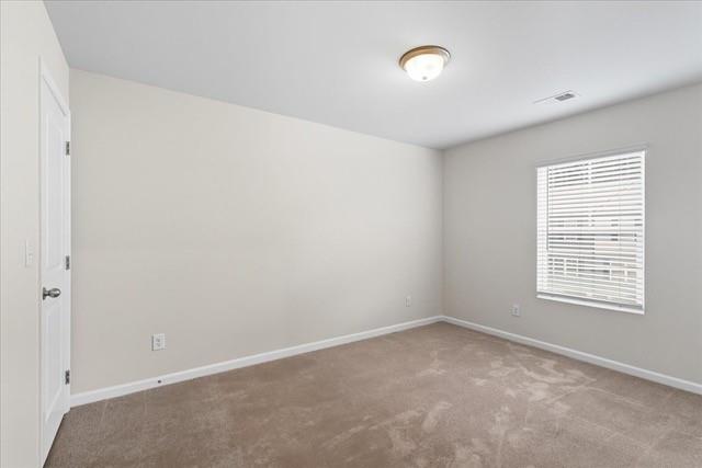 Vacant carpeted room with a window and white blinds.