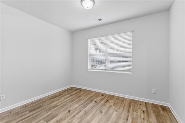 Empty room with wood-look plank flooring and a window with white blinds.