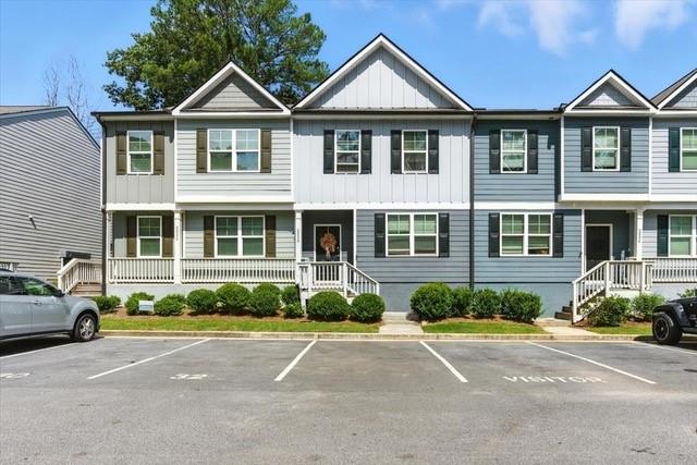 Attached gray and white townhouses with small front porches and parking spaces in front.