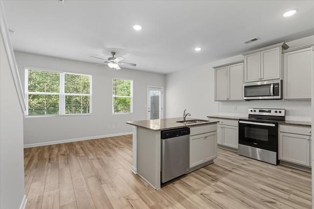 Open kitchen with a center island, stainless steel appliances, and large windows.