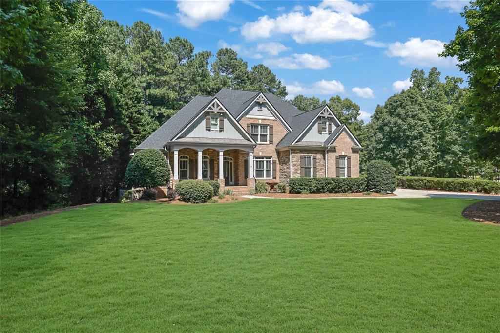 Brick home with multiple gables and a covered porch beyond a broad green lawn.