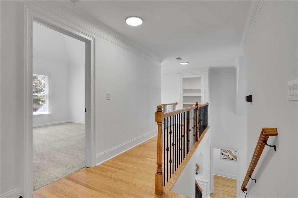 Upstairs hallway with hardwood floors, built-in shelves, and a wood-and-iron stair railing.