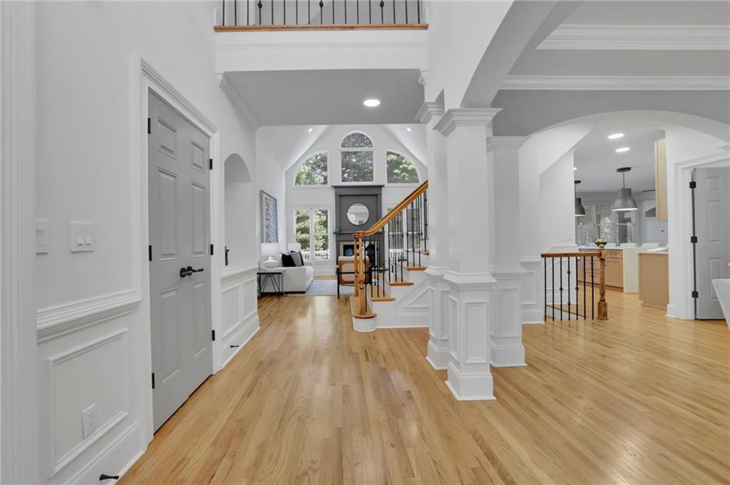 Entry hall with arched windows, hardwood floors, a sitting area, and a staircase.