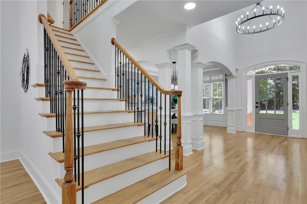 Entry foyer with a sweeping hardwood staircase, black iron balusters, and a glass-paneled front door.