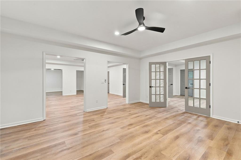 Empty room with light wood-look floors, a tray ceiling, and glass-paneled French doors.