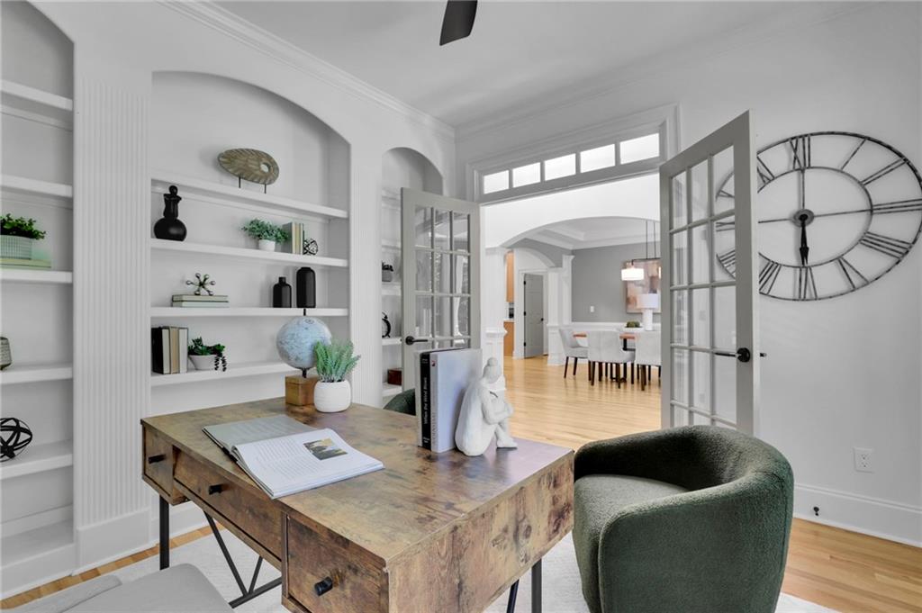 Home office with built-in white shelves, rustic desk, and French doors opening to a dining area.