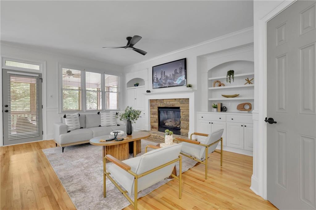 Living room with a stone fireplace, built-in shelves, and seating around a coffee table.