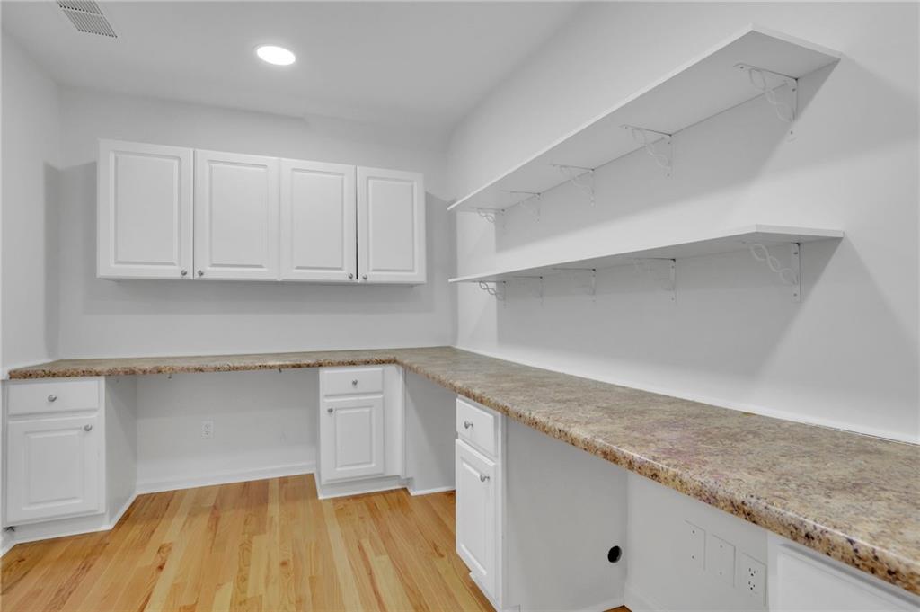 Utility room with L-shaped countertops, white cabinets, open shelves, and hardwood floors.
